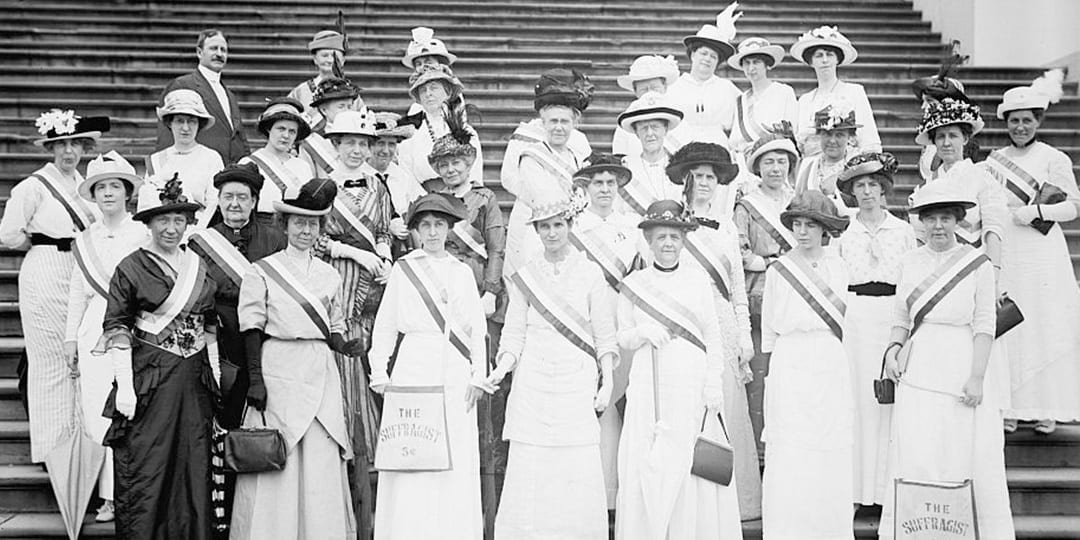 A group of suffragists standing in front of the US Capitol